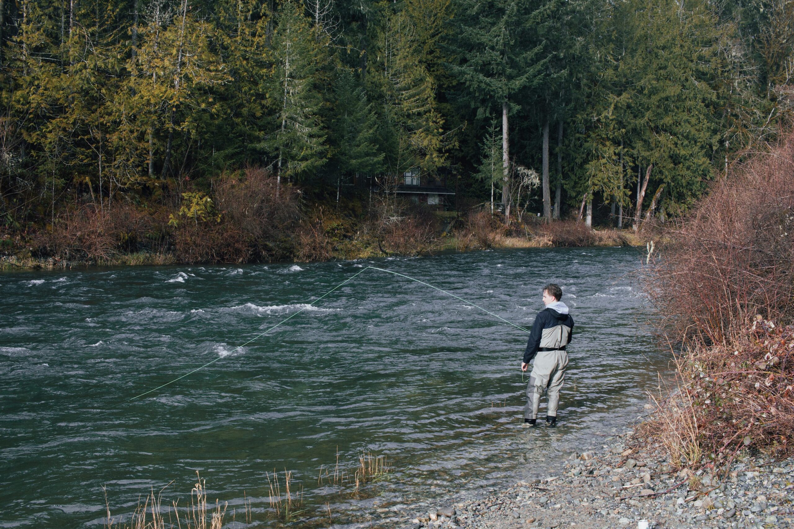 Fly angler standing in a river, photographed by Logan Kuzyk